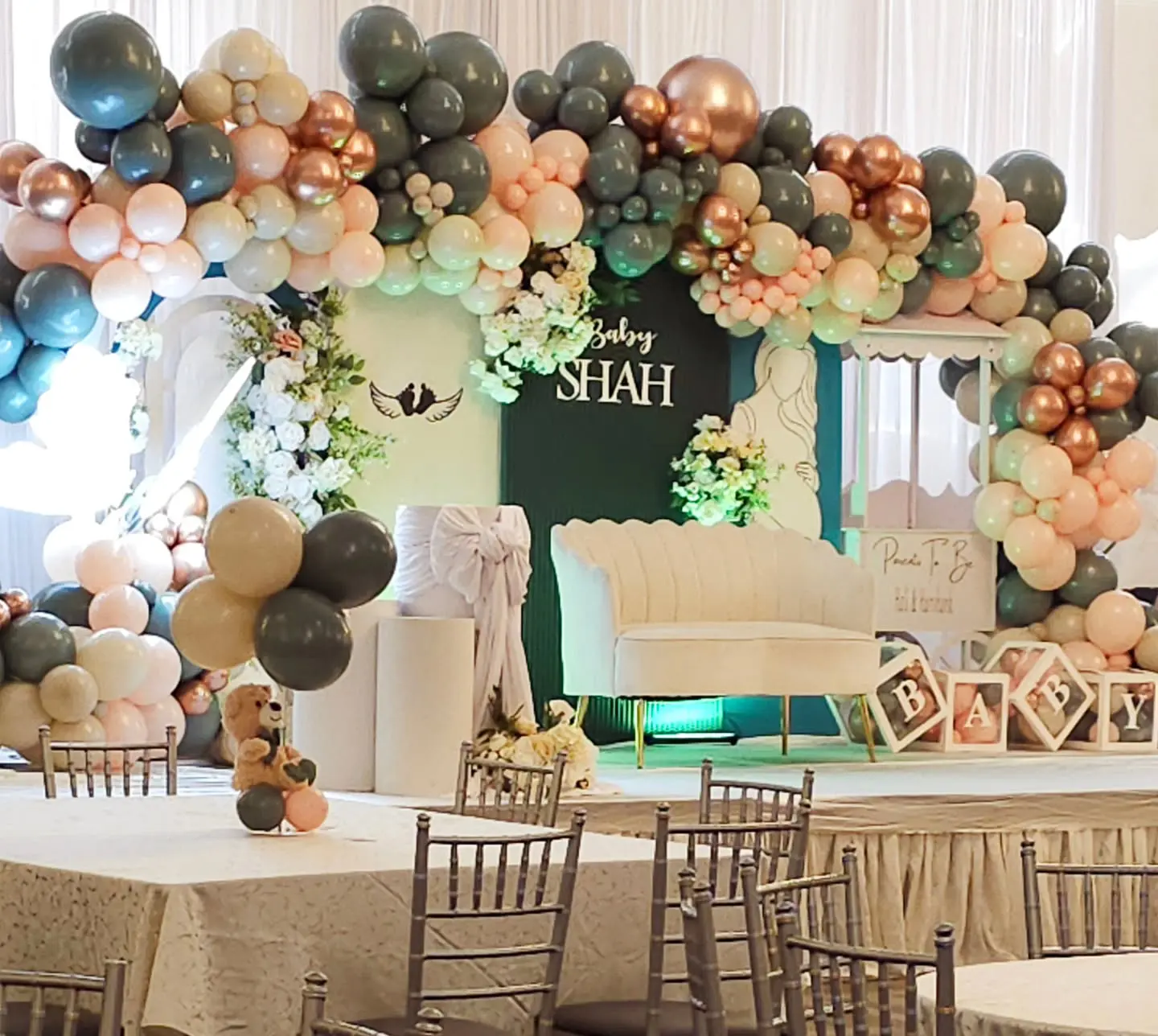 Baby shower rose gold “BABY” blocks in front of balloon garland