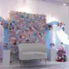 Pastel blue and pink baby shower flower wall backdrop with white seating