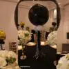 Table centerpiece with black and gold balloon columns and white floral arrangements