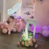 Close-up of pastel balloon decor with floral arrangements and fairy prop for home birthday setup