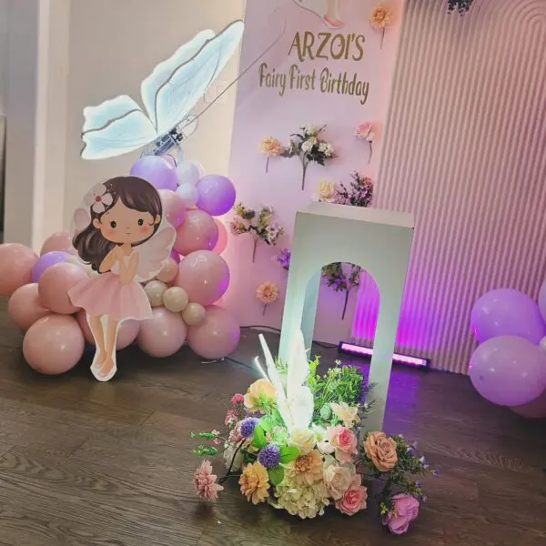 Close-up of pastel balloon decor with floral arrangements and fairy prop for home birthday setup