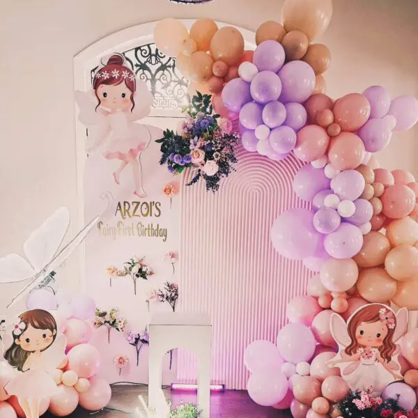 Whimsical first birthday backdrop with pastel balloons and fairy decorations at home
