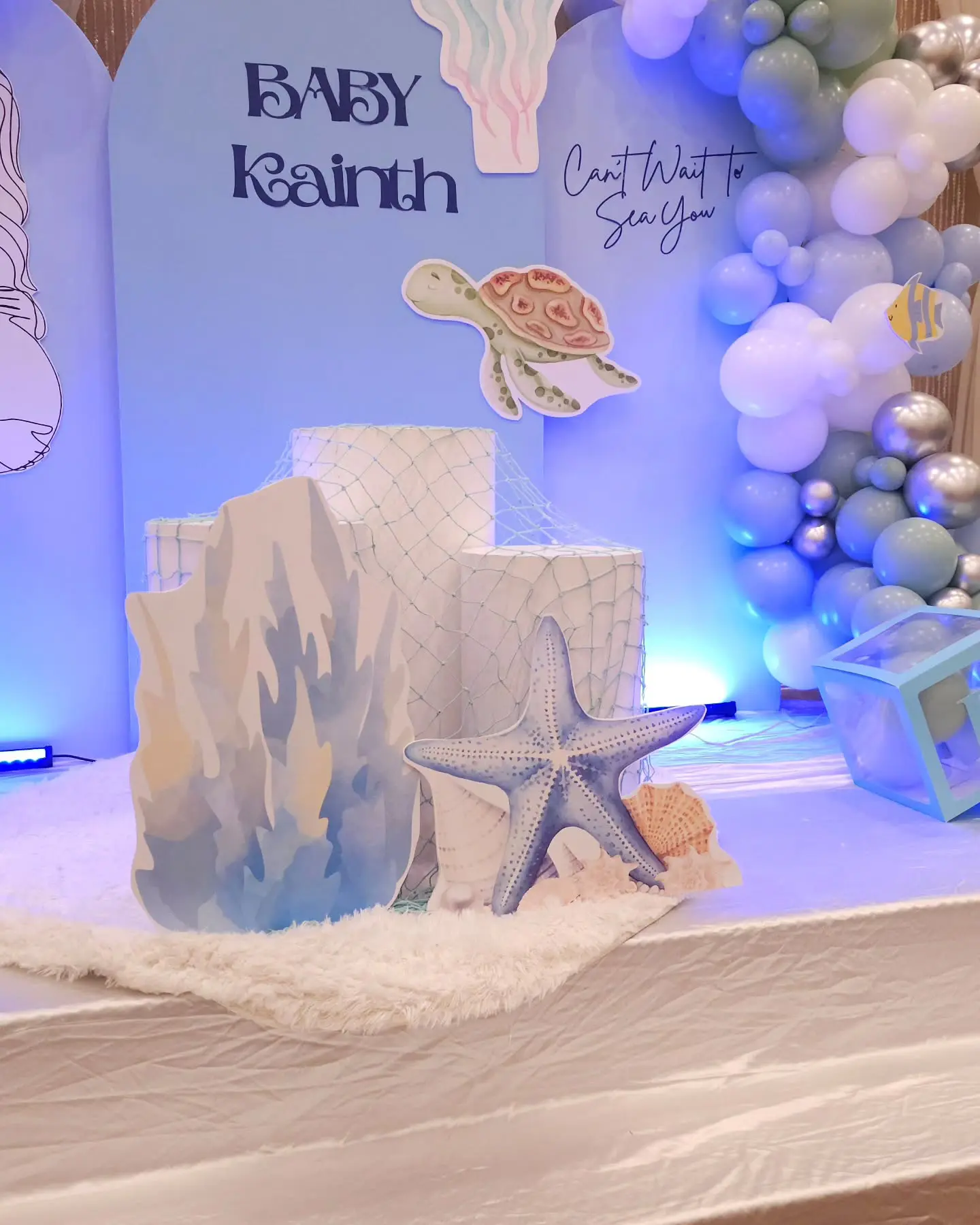 Coral and starfish props with blue baby shower arch