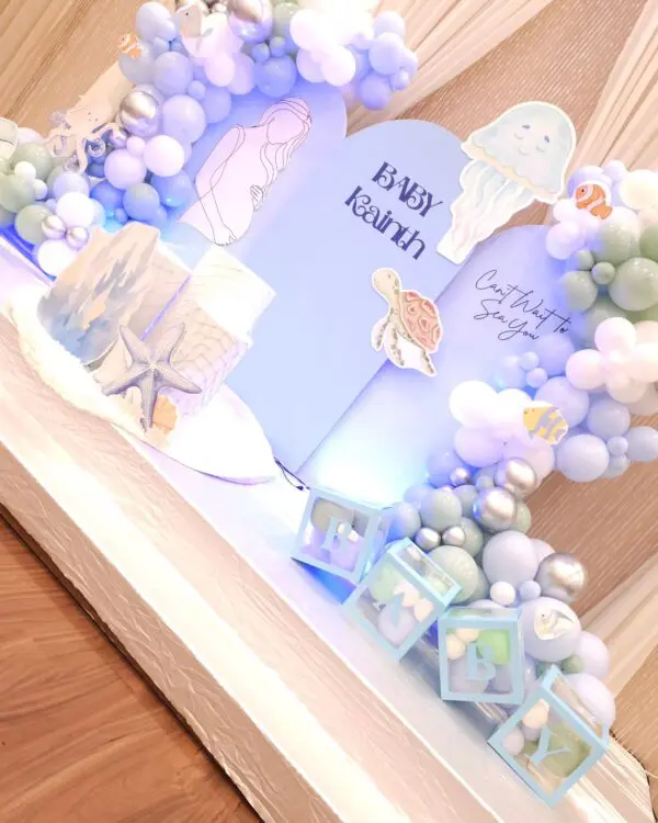 Jellyfish, turtle, and coral props on baby shower backdrop