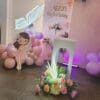 Close-up of pastel balloon decor with floral arrangements and fairy prop for home birthday setup